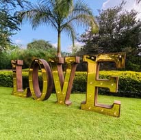 Letras LOVE doradas en jardín para boda